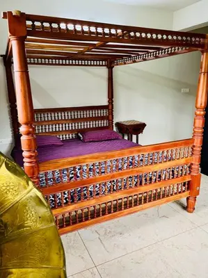 a wooden bed with a wooden frame in a room at Haven Stay Manor in Kotamangalam