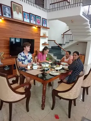 a group of people sitting around a wooden table at Haven Stay Manor in Kotamangalam