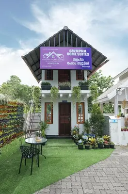 a building with a purple sign on top of it at Swapna Home Suites in Nedumbassery
