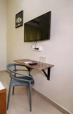 a table with a chair and a television on a wall at Swapna Home Suites in Nedumbassery