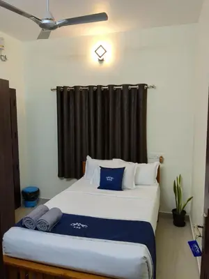a bedroom with a large bed with a black curtain at Swapna Home Suites in Nedumbassery