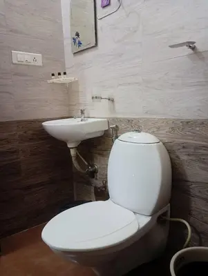 a bathroom with a white toilet and a sink at Swapna Home Suites in Nedumbassery