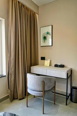a desk and a chair next to a curtain at mesta Hotel in Sultan Bathery