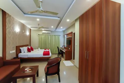 a hotel room with a bed and a couch and a desk at Sreepathi Indraprastha in Guruvāyūr