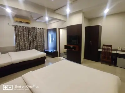 a bedroom with two beds and a desk and a television at Sreepathi Indraprastha in Guruvāyūr