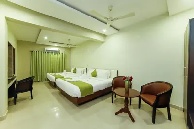 a bedroom with two beds and a table and chairs at Sreepathi Indraprastha in Guruvāyūr