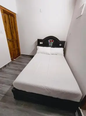 a bed in a small room with a wooden door at Dream Nest Villa Wayanad in Kalpetta