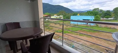 a balcony with a table and chairs and a view of a train at Sathyam Resorts in Dharmapuri