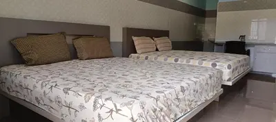 a bedroom with two beds and a kitchen at Sathyam Resorts in Dharmapuri