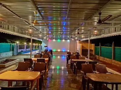 a dining room with tables and chairs and lights at Sathyam Resorts in Dharmapuri