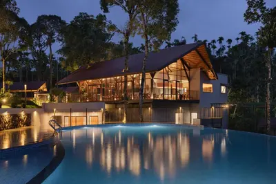 a house with a swimming pool in front of a building at Sterling Lontano Waterfront Wayanad in Meppādi