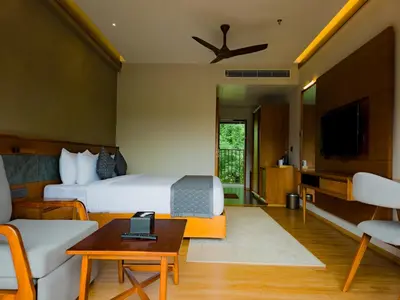 a hotel room with a bed and a living room at Sterling Lontano Waterfront Wayanad in Meppādi