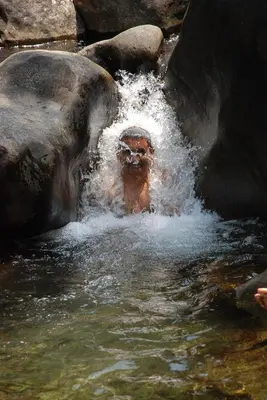 a man is in the water near some rocks at Great Hornbill Serviced Villa , Nilambur in Kālikāvu