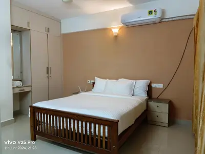 a bedroom with a bed with a air conditioner on the wall at VVP Service Apartments & Airport Suits in Cochin