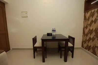 a dining room table with two chairs and a table at VVP Service Apartments & Airport Suits in Cochin