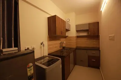 a small kitchen with wooden cabinets and a sink at VVP Service Apartments & Airport Suits in Cochin