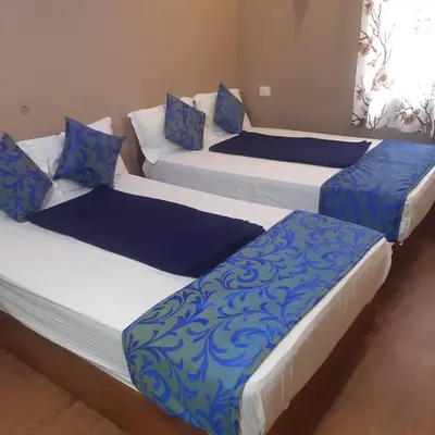 three beds in a room with blue and white pillows at RIVERVIEW HOMESTAy in Vālpārai