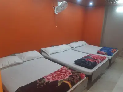 two beds in a room with an orange wall at RIVERVIEW HOMESTAy in Vālpārai