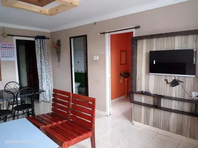 a living room with a bench and a flat screen tv at RIVERVIEW HOMESTAy in Vālpārai