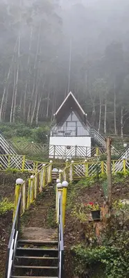 a stairway leading to a white house in the fog at The Soul Of Vattavada in Vattavada
