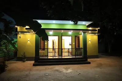 a small green house with a balcony at night at Josebaa Inn in Vythiri