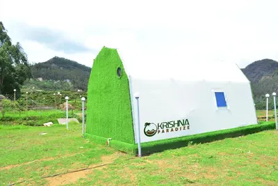 a white building with a green wall in a field at Kodaikanal Luxuries Glamp - Krishna Paradize in Kūkkāl
