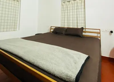 a bed in a room with two windows at Churuli Bungalow in Ambalavayal