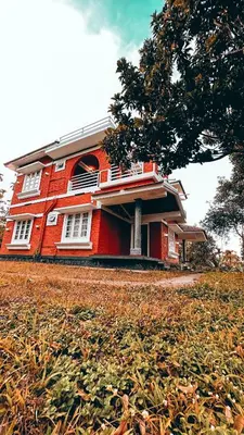 a red building sitting on top of a field at Churuli Bungalow in Ambalavayal