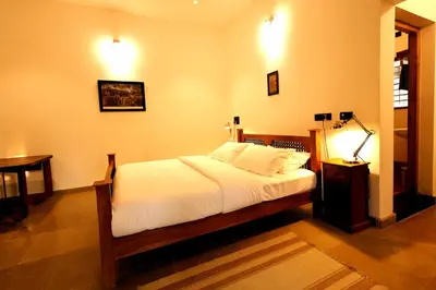 a bedroom with a bed and a table and a lamp at The Hidden Pearl Palakkad by Chakolas Hospitality in Thenkurissi