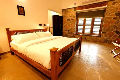 a bedroom with a large bed with a stone wall at The Hidden Pearl Palakkad by Chakolas Hospitality in Thenkurissi