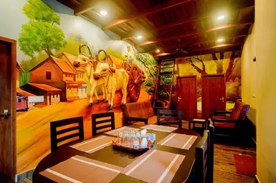 a dining room with a mural of a cow on the wall at Falcon Riverview Resorts in Kuttampuzha