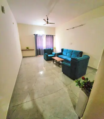 a living room with a blue couch and a table at Nandan Elite in Mysore