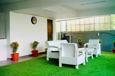 a patio with white chairs and a table on grass at Elite Enclave - Mysore - 2BHK Luxury Serviced Apartments in Mysore