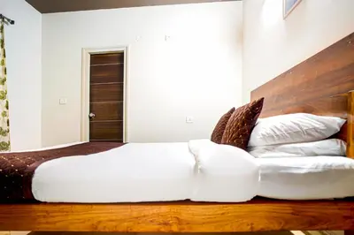 a bedroom with a white bed with a wooden headboard at Elite Enclave - Mysore - 2BHK Luxury Serviced Apartments in Mysore