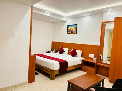 a hotel room with a bed and a table at Hotel Starfinch Inn in Kushālnagar