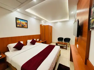 a hotel room with a bed and a flat screen tv at Hotel Starfinch Inn in Kushālnagar