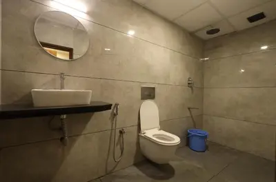 a bathroom with a toilet and a sink and a mirror at Hotel president park Coimbatore in Coimbatore