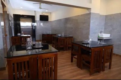 a restaurant with wooden tables and chairs and a kitchen at Hotel president park Coimbatore in Coimbatore