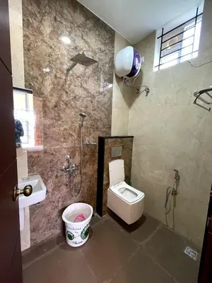 a bathroom with a toilet and a shower and a sink at Siesta Inn- Mountain View in Kodaikānāl