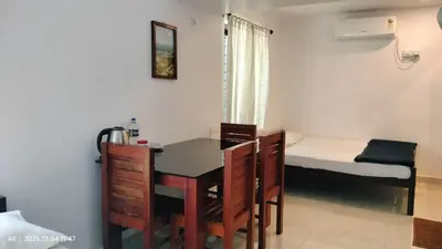 a room with a desk and a table and a bed at Palatty Residency in Angamali