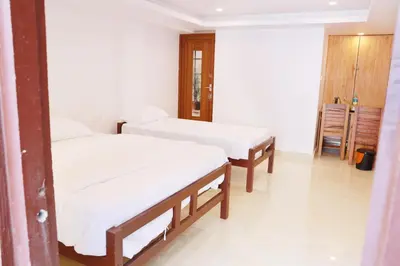 two beds in a room with white sheets at Palatty Residency in Angamali