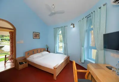 a bedroom with a bed and a desk and a television at Kairali - The Ayurvedic Healing Village in Palakkad