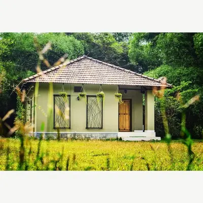 a small house with a door in a field at The Road's End in Gonikoppal