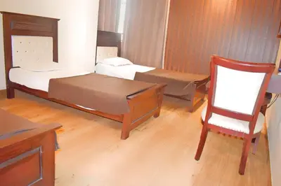 a small room with two beds and a chair at SAK Royal Residency 1 km from Railway Station in Mysore