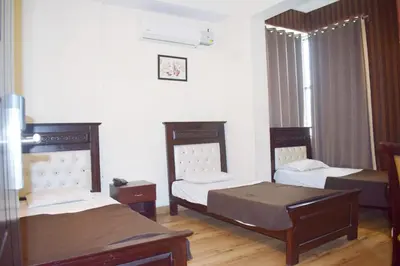 a room with three beds and a window at SAK Royal Residency 1 km from Railway Station in Mysore