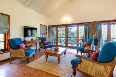 a living room with blue chairs and a desk at Pepper Trail in Sultan Bathery