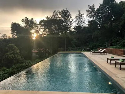 a swimming pool with two benches and the sun setting at Pepper Trail in Sultan Bathery