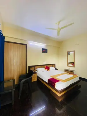 a bedroom with a bed and a chair in it at O'live Inn Wayanad Apart-Hotels in Vaduvanchal