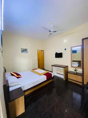 a bedroom with a bed and a desk in it at O'live Inn Wayanad Apart-Hotels in Vaduvanchal