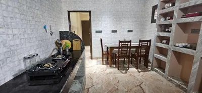 a kitchen with a stove and a table with chairs at SHI's Thulasi 2BHK in Coimbatore Near to Karpagam College, Palakkad Highway, Rathinam College and More in Coimbatore